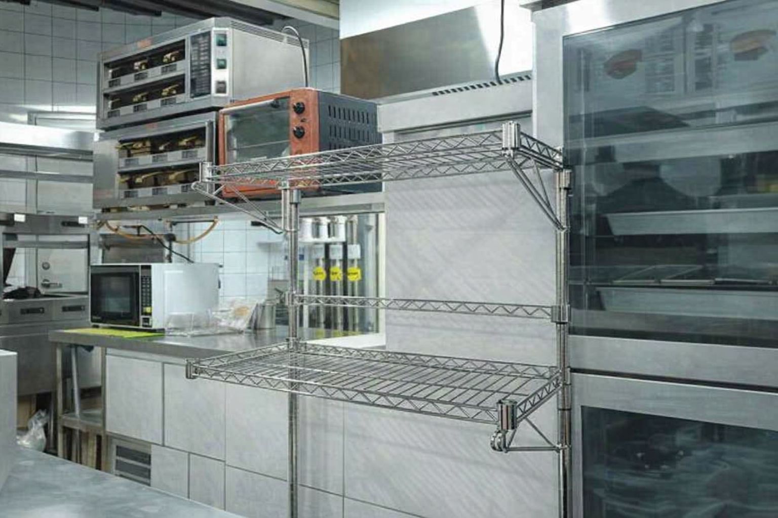 Edelstahlregale in einer Restaurantküche mit Öfen und Arbeitsflächen.
