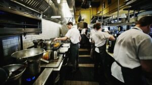 Enge Restaurantküche mit Köchen, Pfannen und dichtem Durchgang