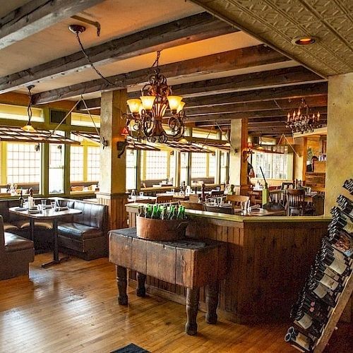 Rustikales Wirtshaus mit Holzbänken, Tischen und warmem Kronleuchterlicht